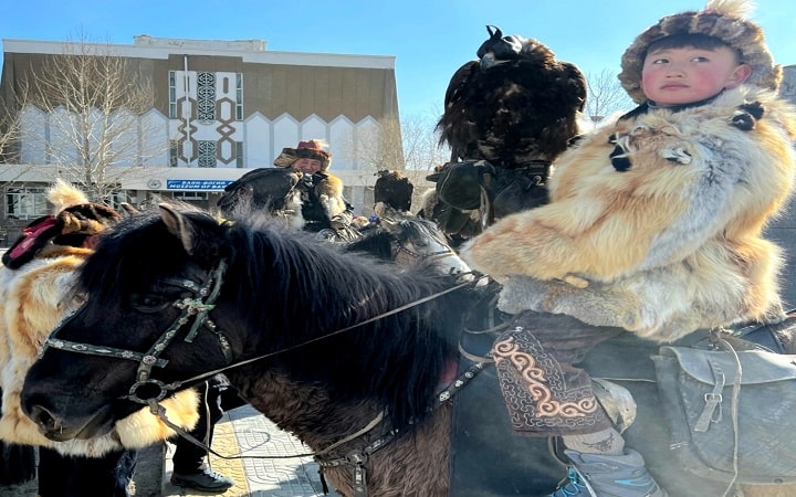 Eagle hunter boy being the center of attention for photographers at nauryz festival in western Mongolia